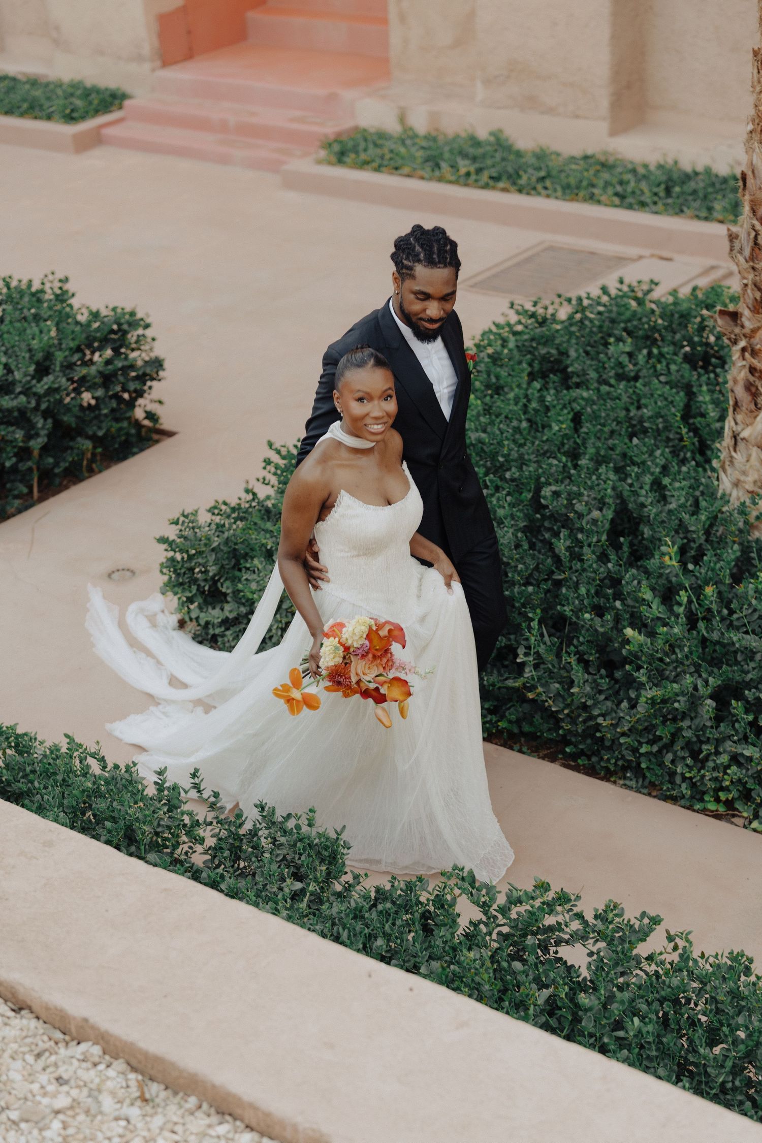 A romantic wedding couple sharing an intimate moment on a tree-lined pathway.