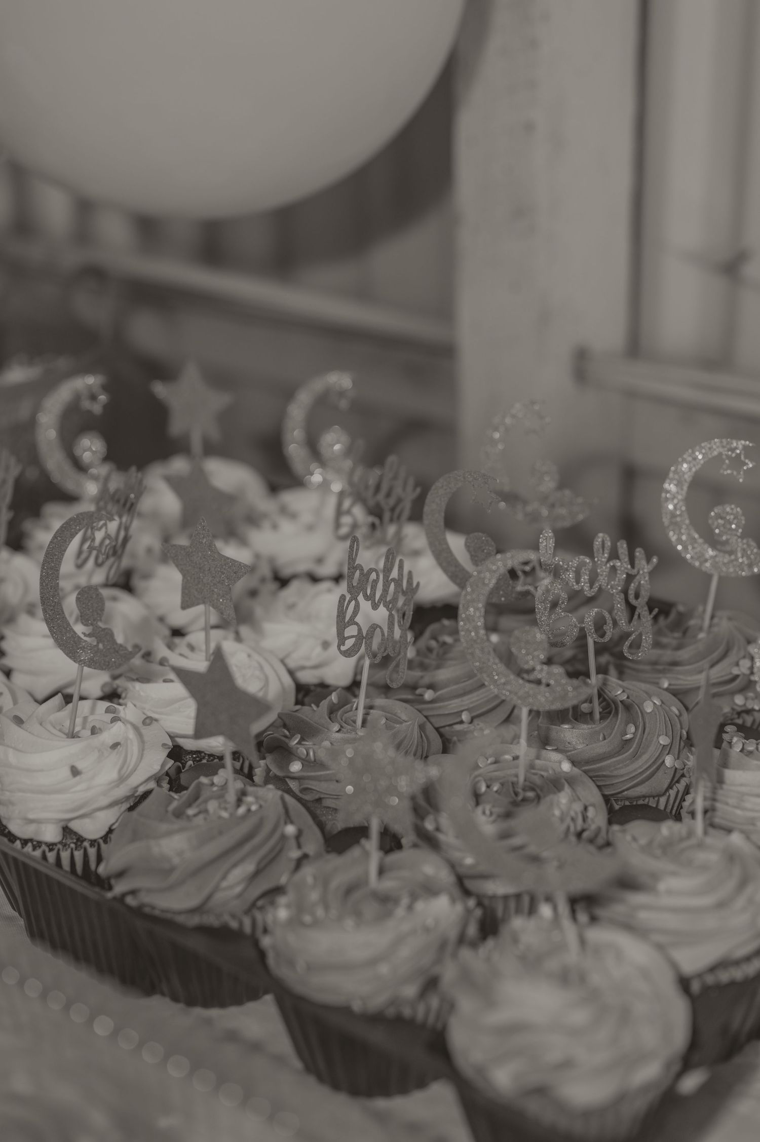 Black and white photo of decorated cupcakes with moon and star toppers arranged on a dessert table. photo by Samantha Campbell imagery