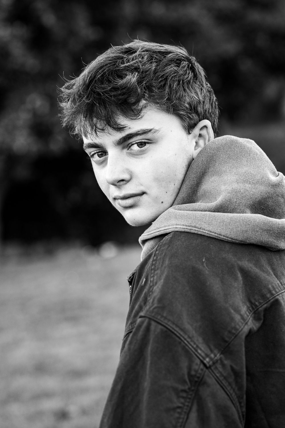 A black and white portrait sequence showing someone turning their head while wearing a casual jacket.