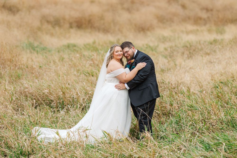 Romantic couple in wedding attire standing together in a golden grassy meadow in Dakota Dunes, South Dakota.