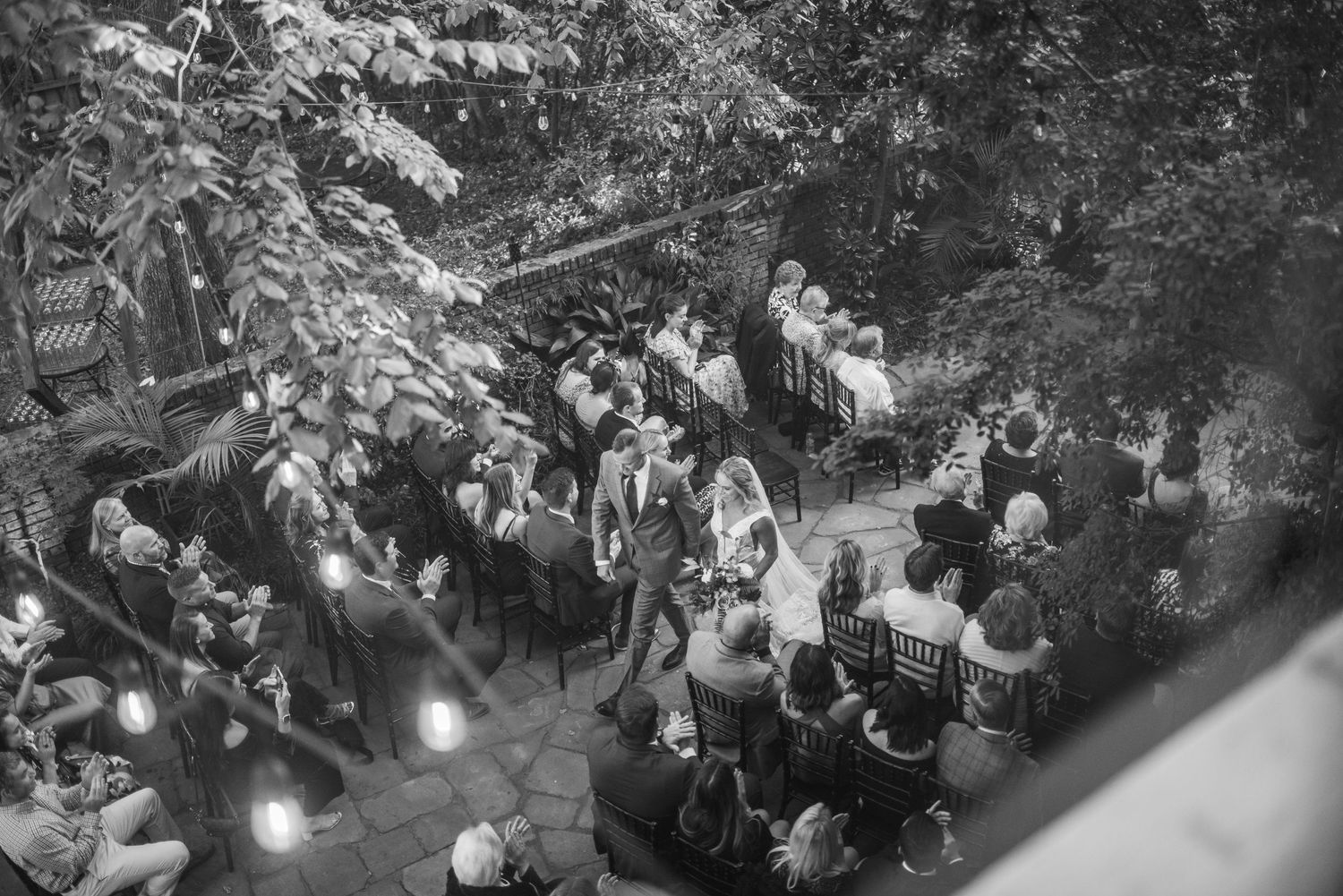 Vintage black and white photograph of a crowded outdoor wedding ceremony under trees.
