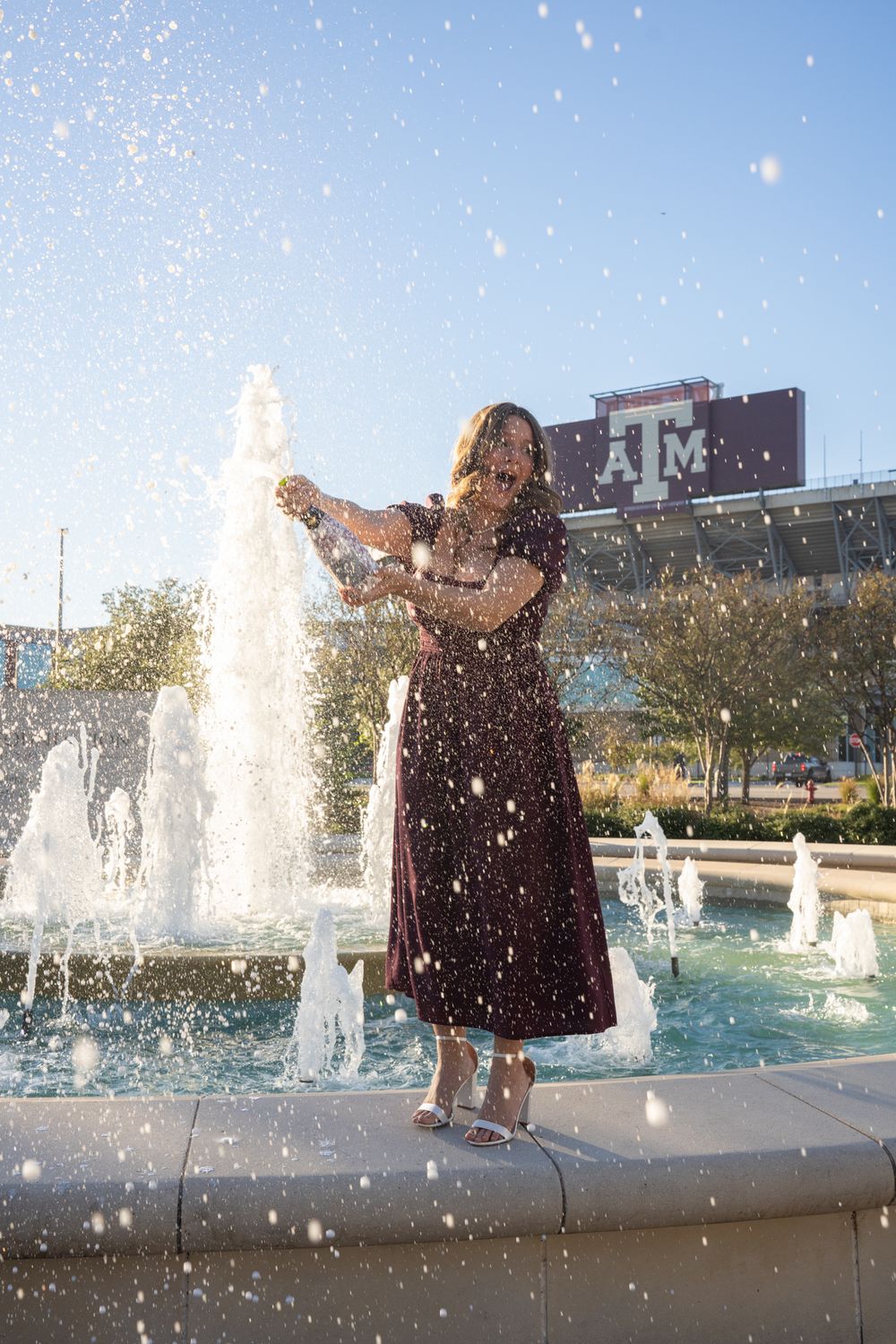 A Texas A&M graduate popping a bottle of champagne on campus to celebrate their graduation in College Station.