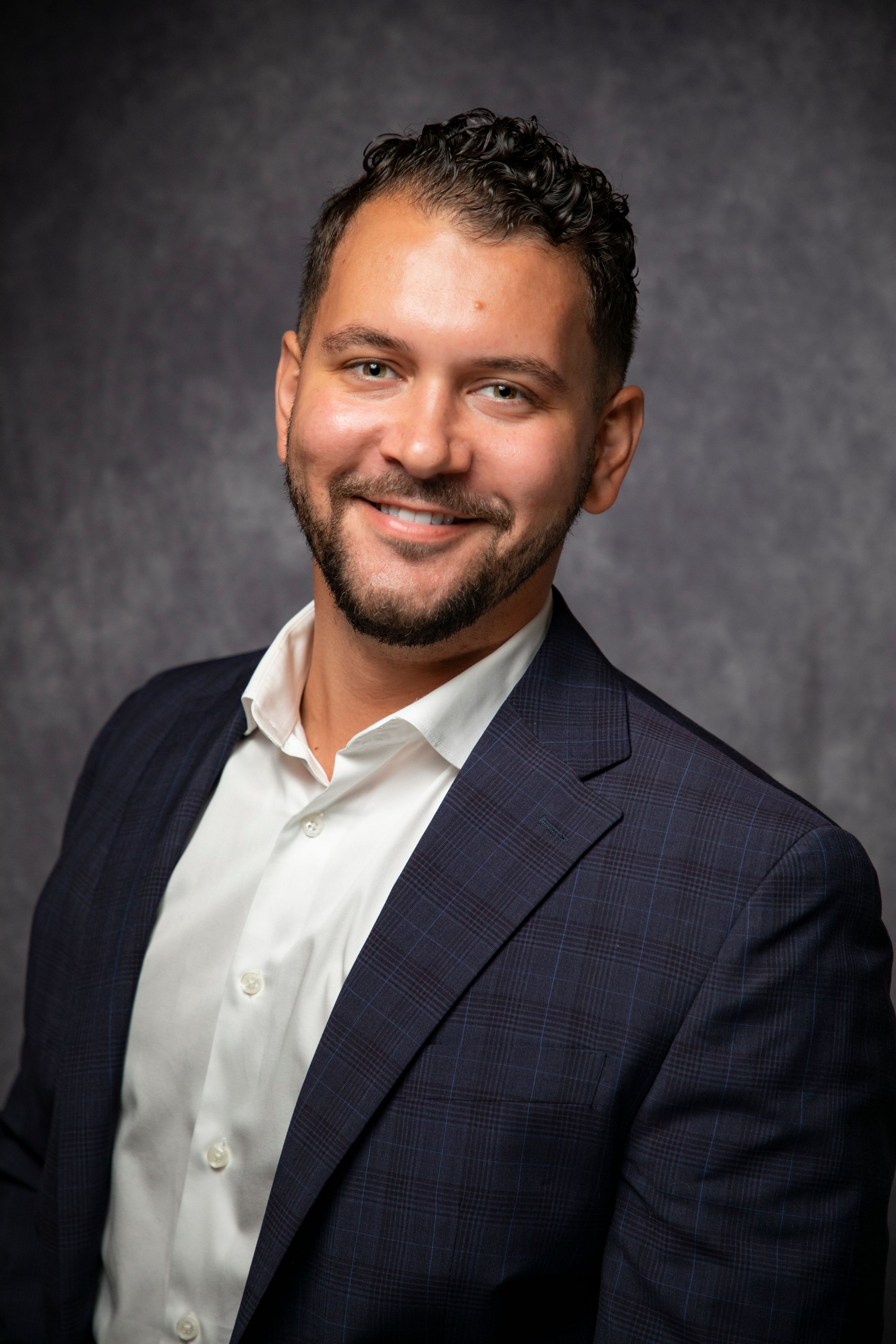 Professional headshot series showing warm smile against dark studio background.