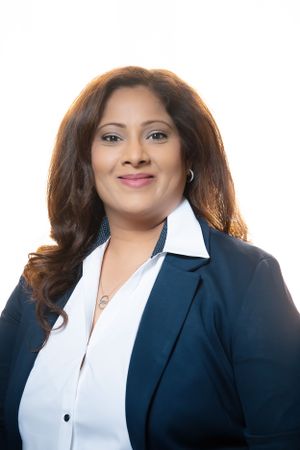 Professional portrait of someone in business attire with a navy blazer and white blouse.