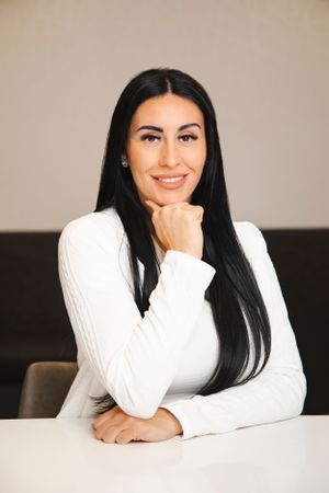Woman in white sweater sitting at desk in professional headshot series.