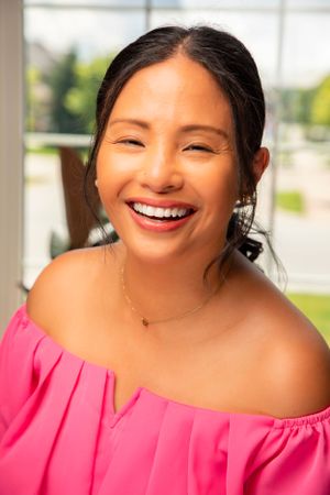 Woman in bright pink off-shoulder top smiling warmly in a series of candid expressions.