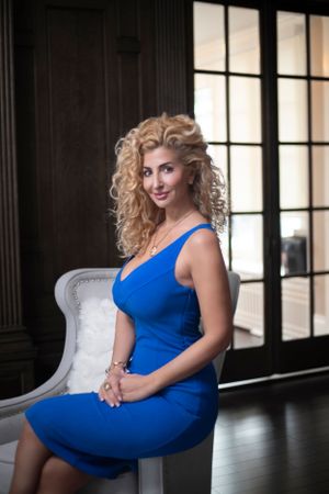 Glamour photography session featuring poses in a vibrant blue dress on a dark set with windows.
