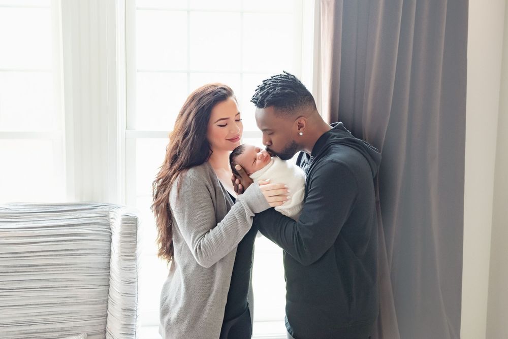 Parents admiring their newborn baby in bright modern room.