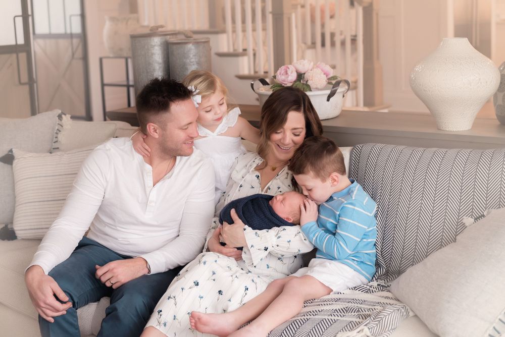 A family relaxing together on a cozy grey sofa in their living room.
