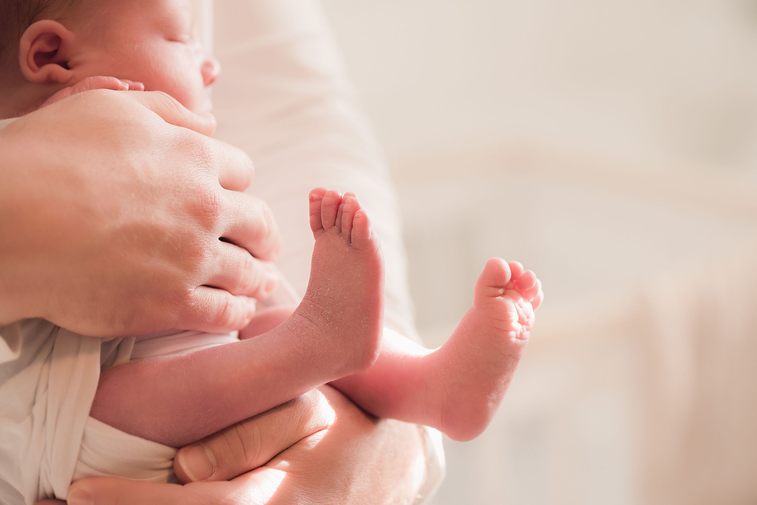 Close-up view of tiny baby feet being gently held by adult hands.