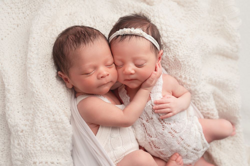 Twin newborn babies boy and girl cuddling