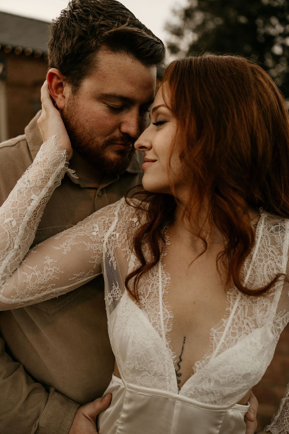 Intimate wedding portrait of couple in warm earthy tones with bride wearing delicate lace dress.