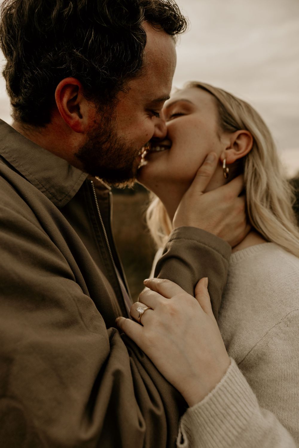 A romantic couple sharing an intimate moment in warm lighting while wearing casual fall attire.