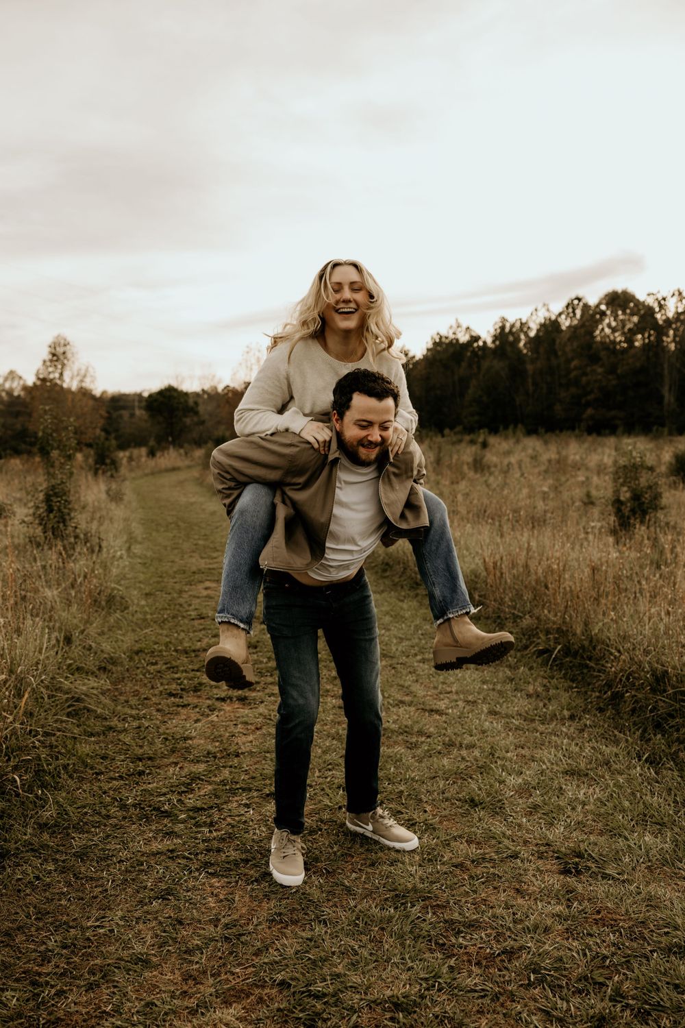 Playful piggyback ride moment captured in a rustic field during golden hour.