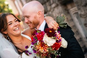 A wedding couple shares tender moments with vibrant autumn flowers in a romantic outdoor setting.