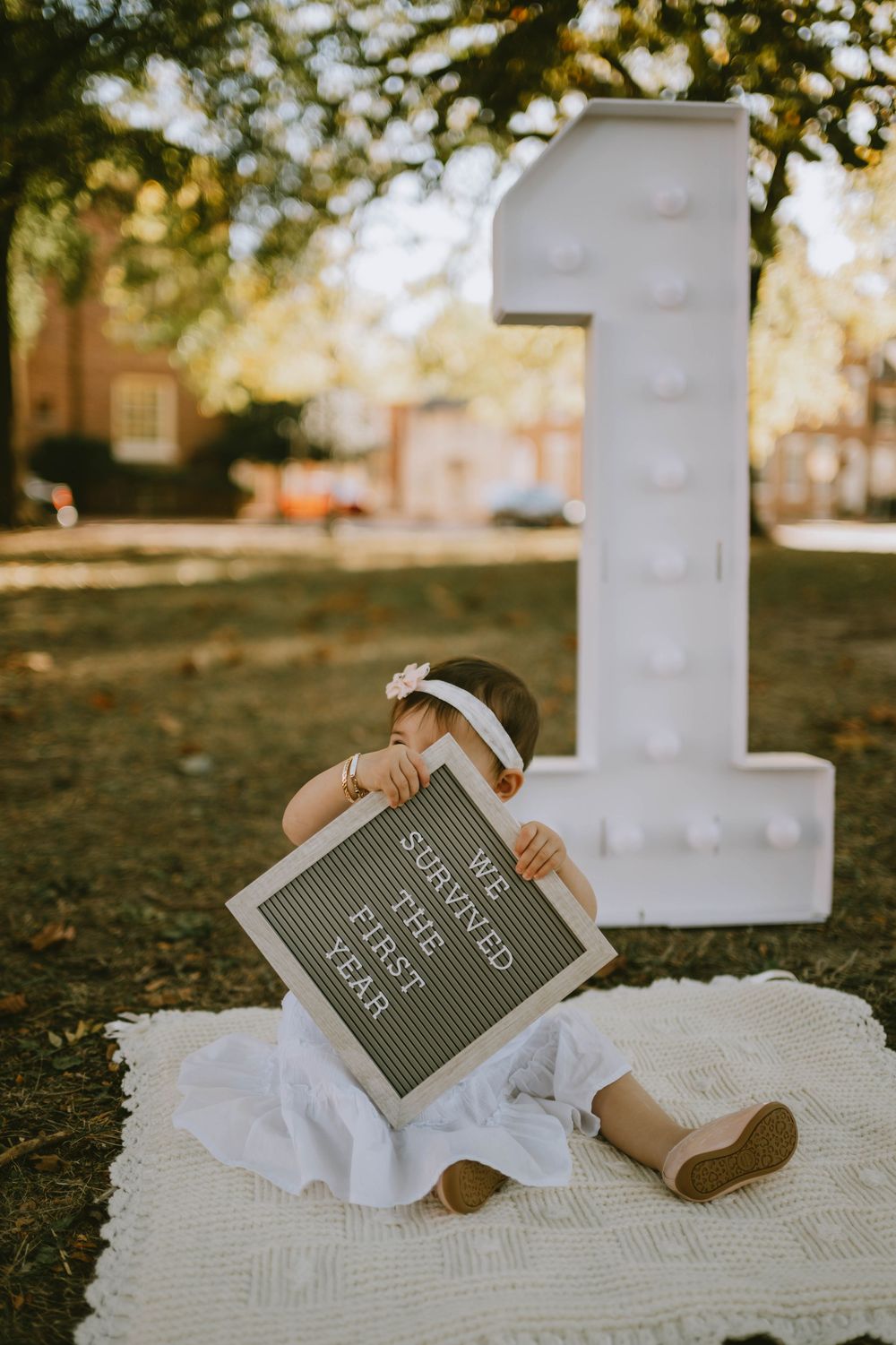 Vintage chalkboard with text lying on white blanket outdoors in autumn setting.