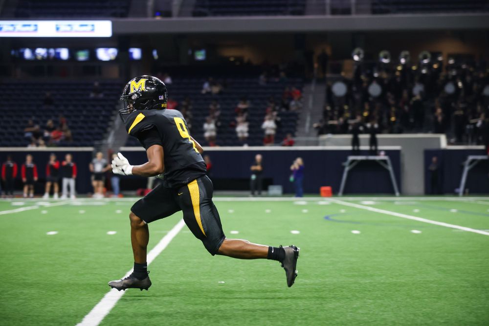 A sequence of football players running and training drills on an indoor field at night.