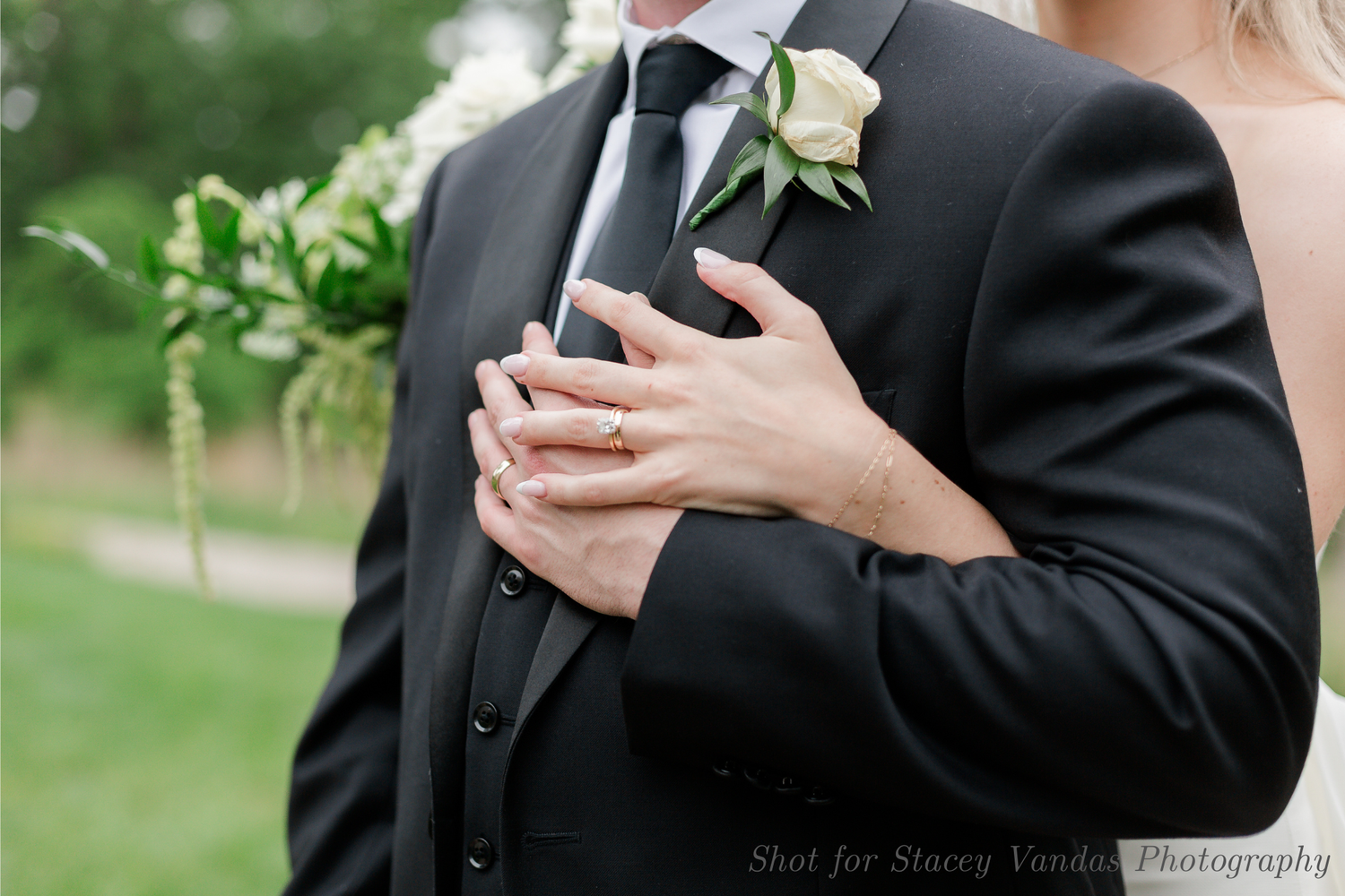 A bride and groom embrace, a closeup of their hands wrapped around the groom's chest, captured by their STL wedding photographer.