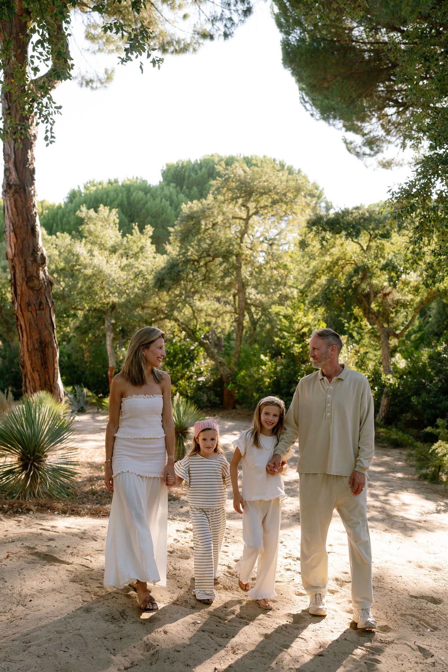 Comporta family photo session showing elegant parents walking with two small daughters along pine trees