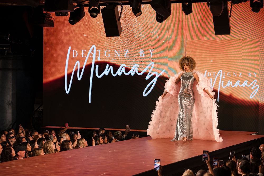 Fashion show scene with illuminated stage and dramatic lighting effects.