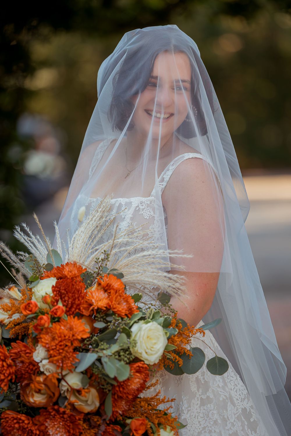 Bridal portrait series showing autumn-themed wedding bouquet with orange carnations and white roses under flowing veil.