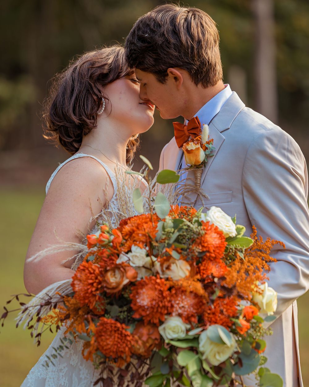 A romantic wedding moment captured in a garden with a vibrant orange and green floral bouquet.
