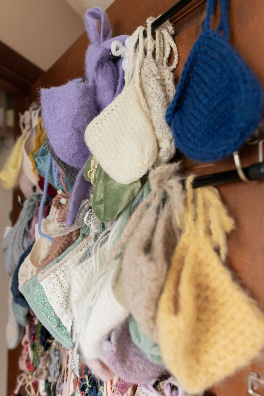 Variety of knitted wool garments in purple, blue, and yellow hanging on display.