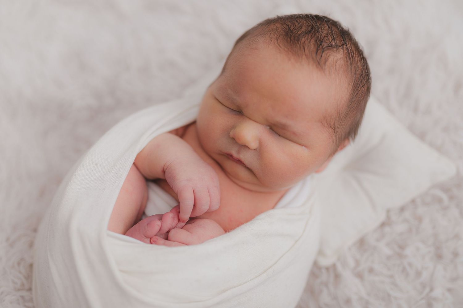 Peaceful sleeping newborn wrapped in white swaddle during professional photo session. Photographer. Hull. East Yorkshire. Photography