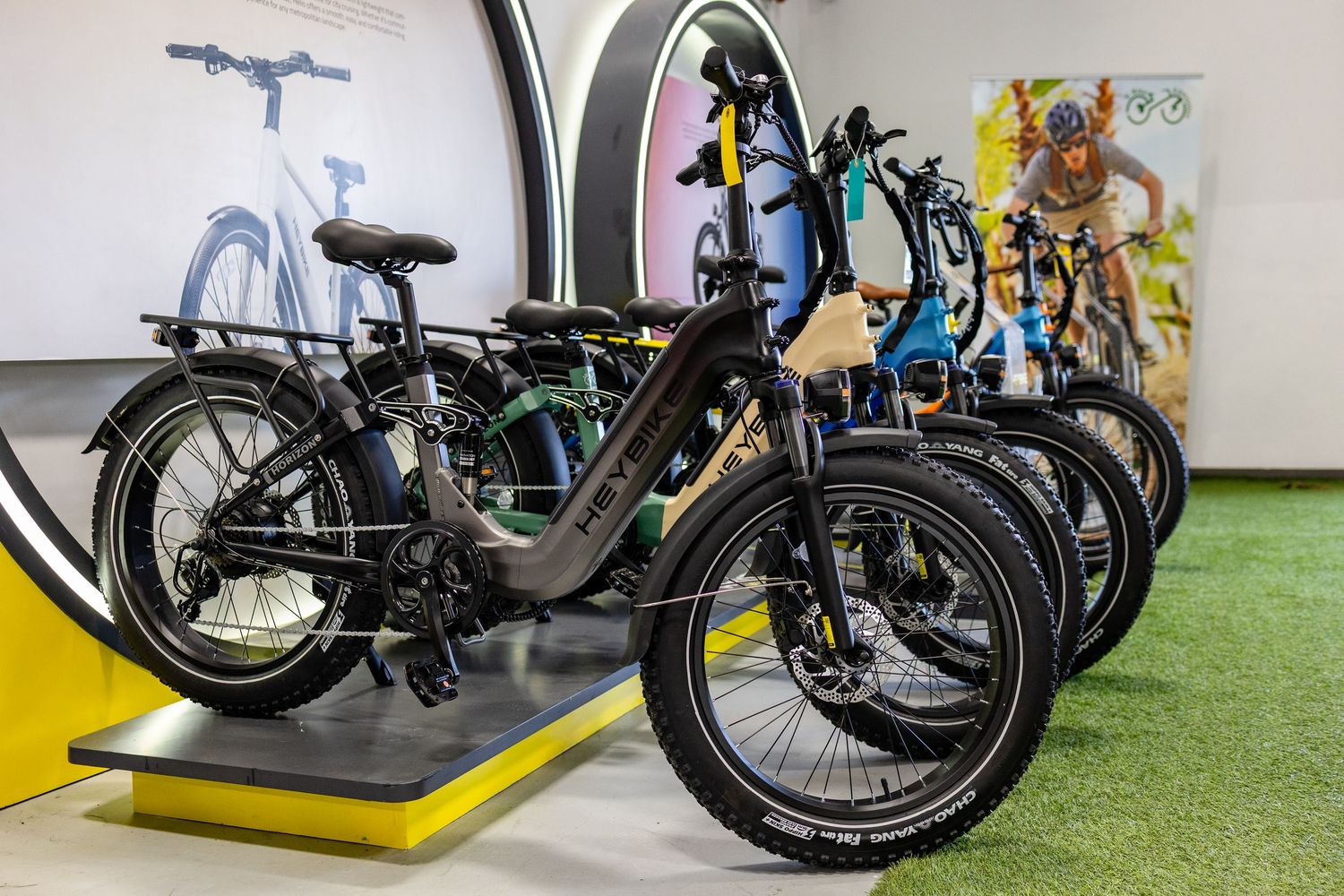 Display of black electric bikes in a modern showroom with artificial grass flooring.
