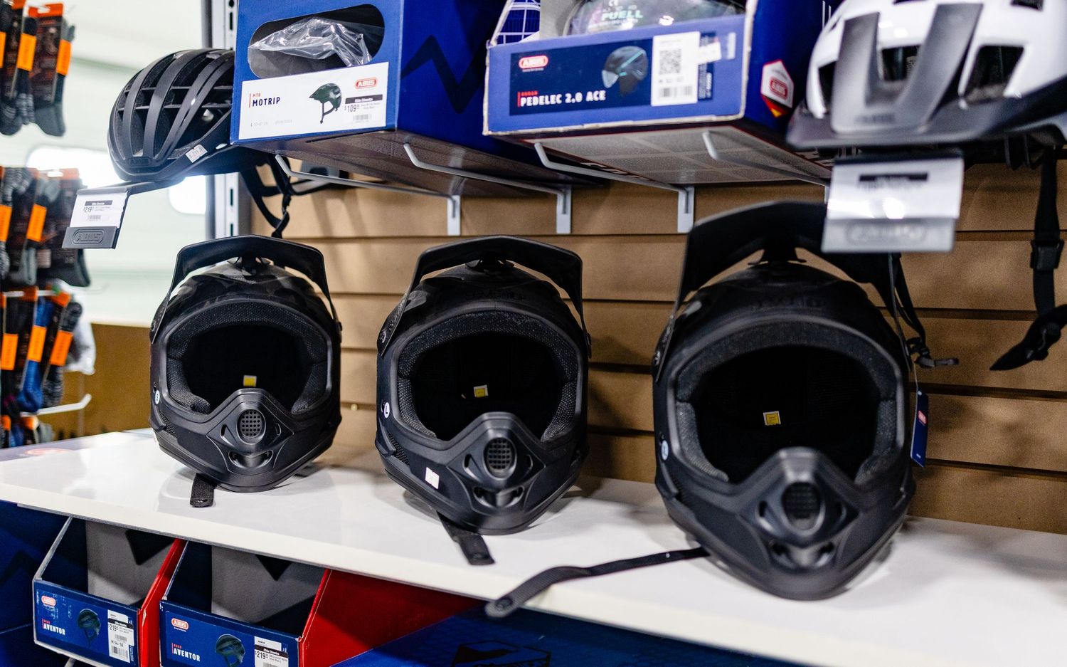 Row of black cycling helmets displayed on retail shelving.