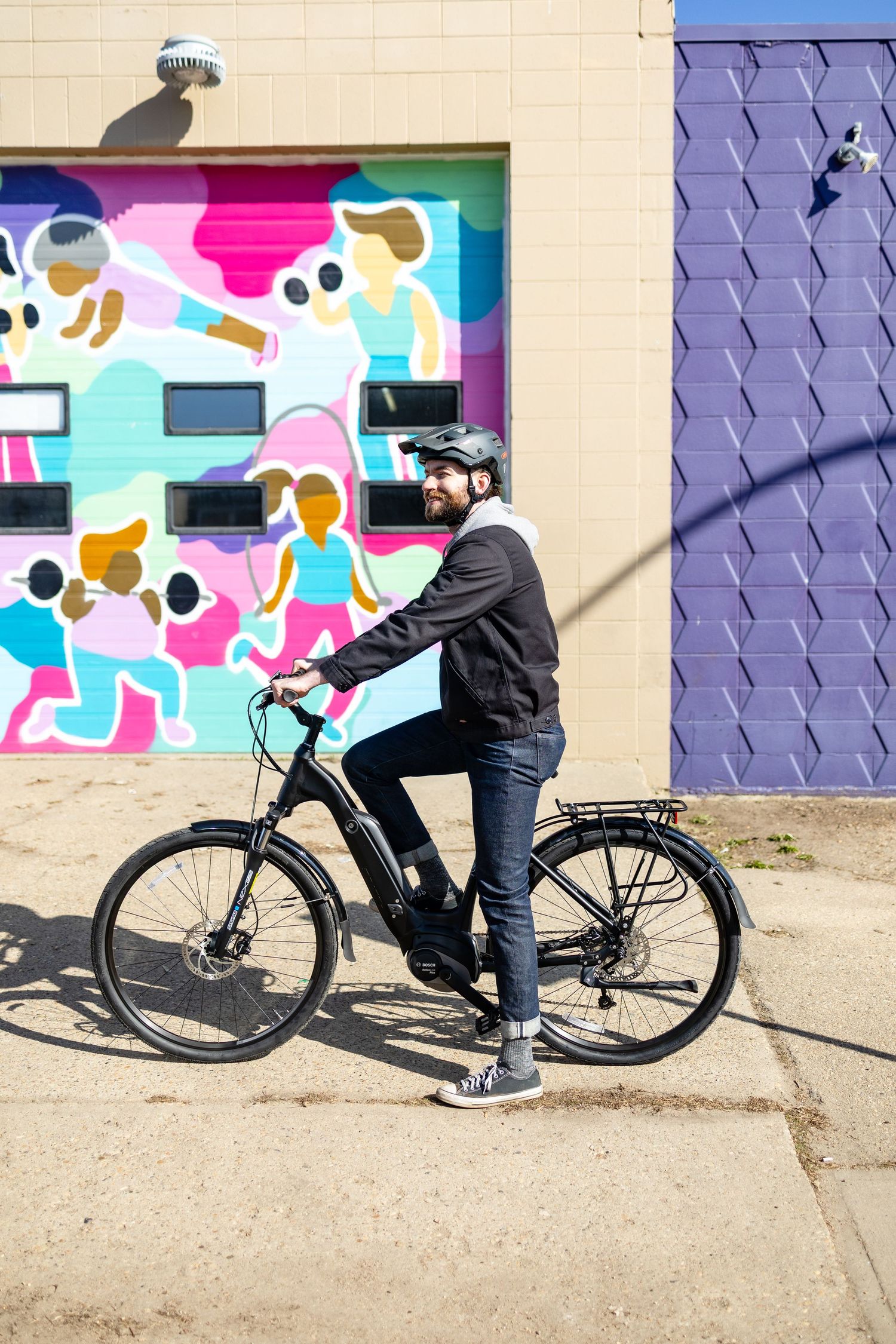 Electric bike parked against a wall with colorful street art mural.