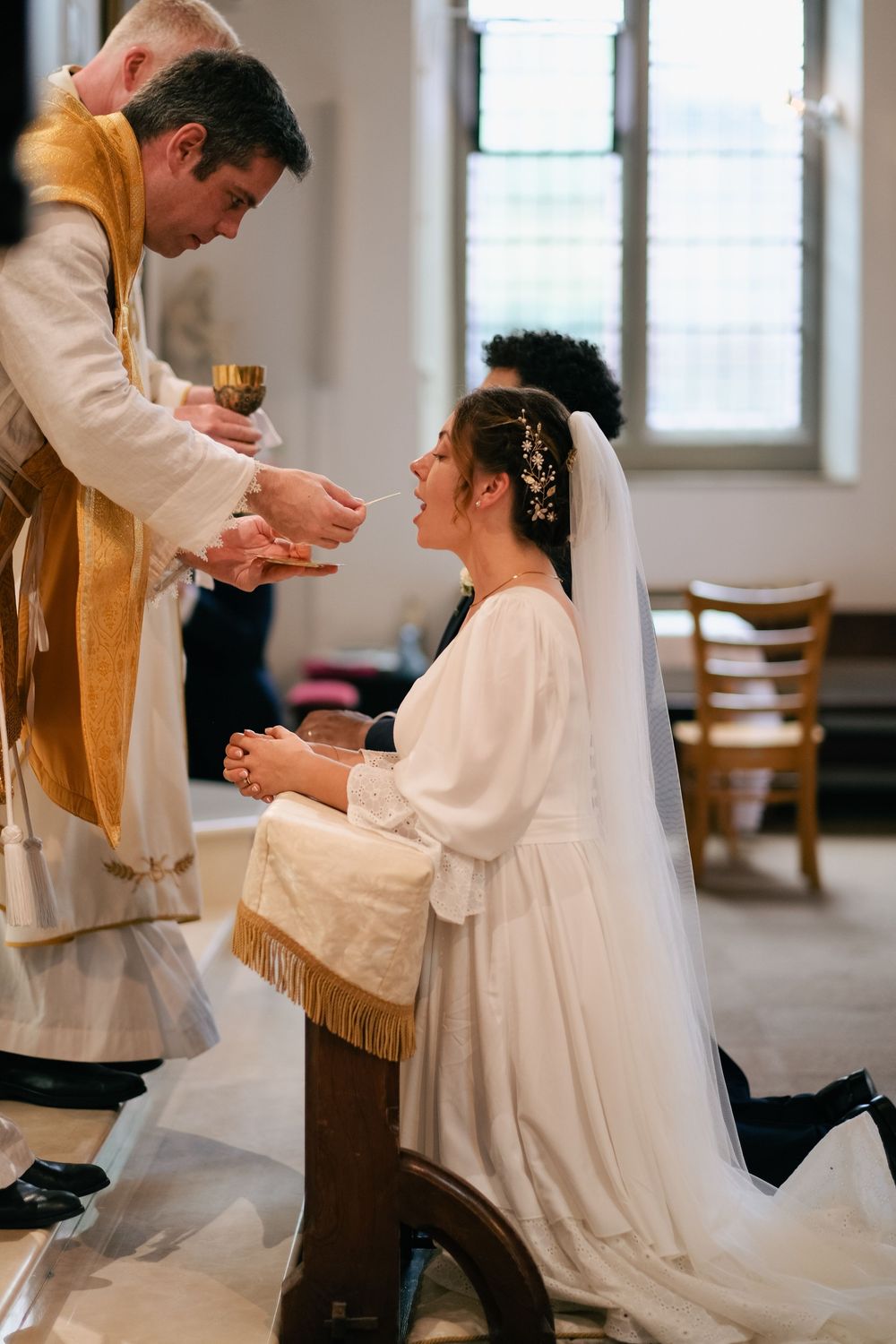 A couple shares an intimate moment during their wedding ceremony in a light-filled church setting.