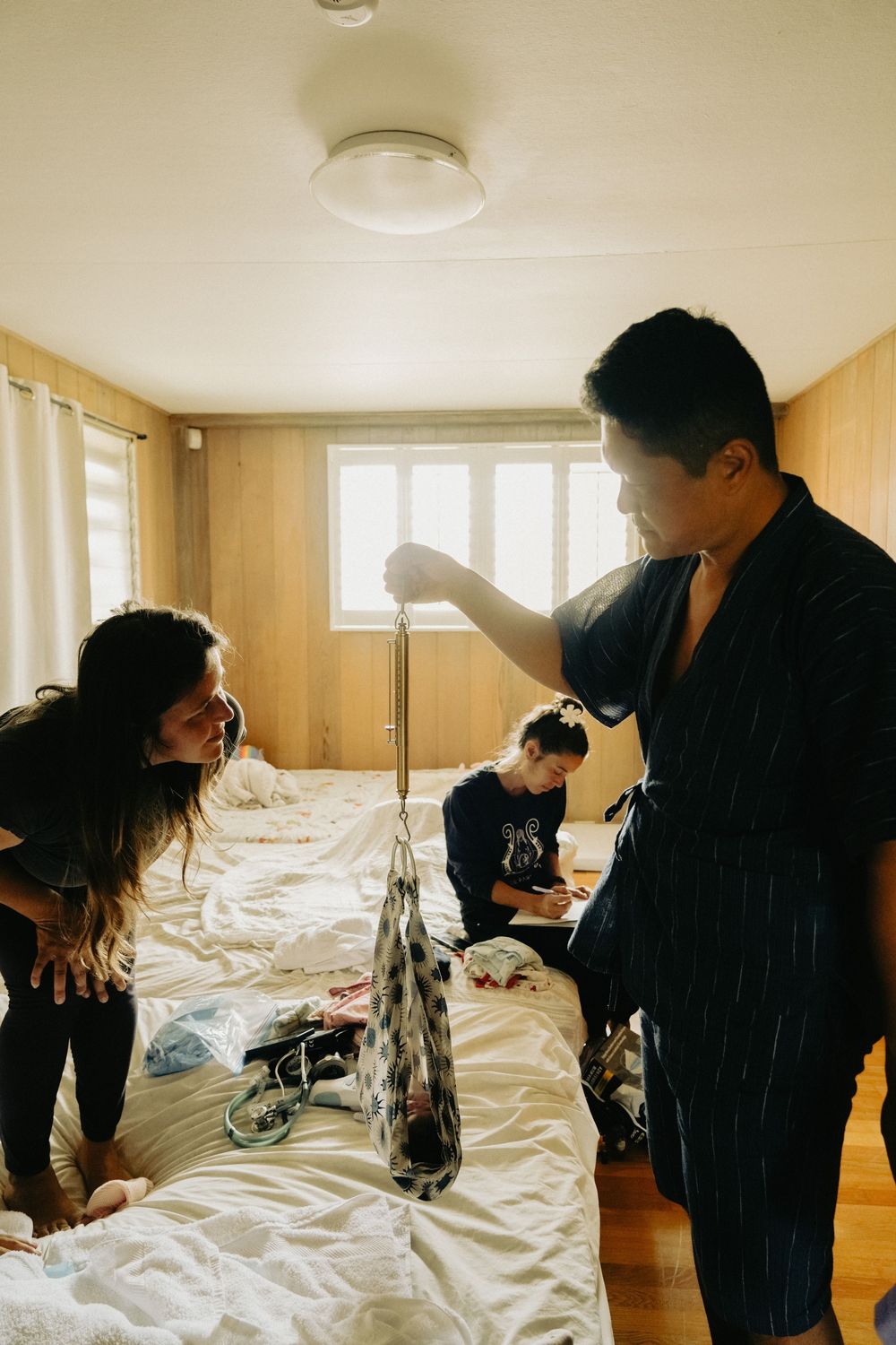People in a room with plastic-covered surfaces preparing for a paint or renovation project. Oahu Newborn Photographer