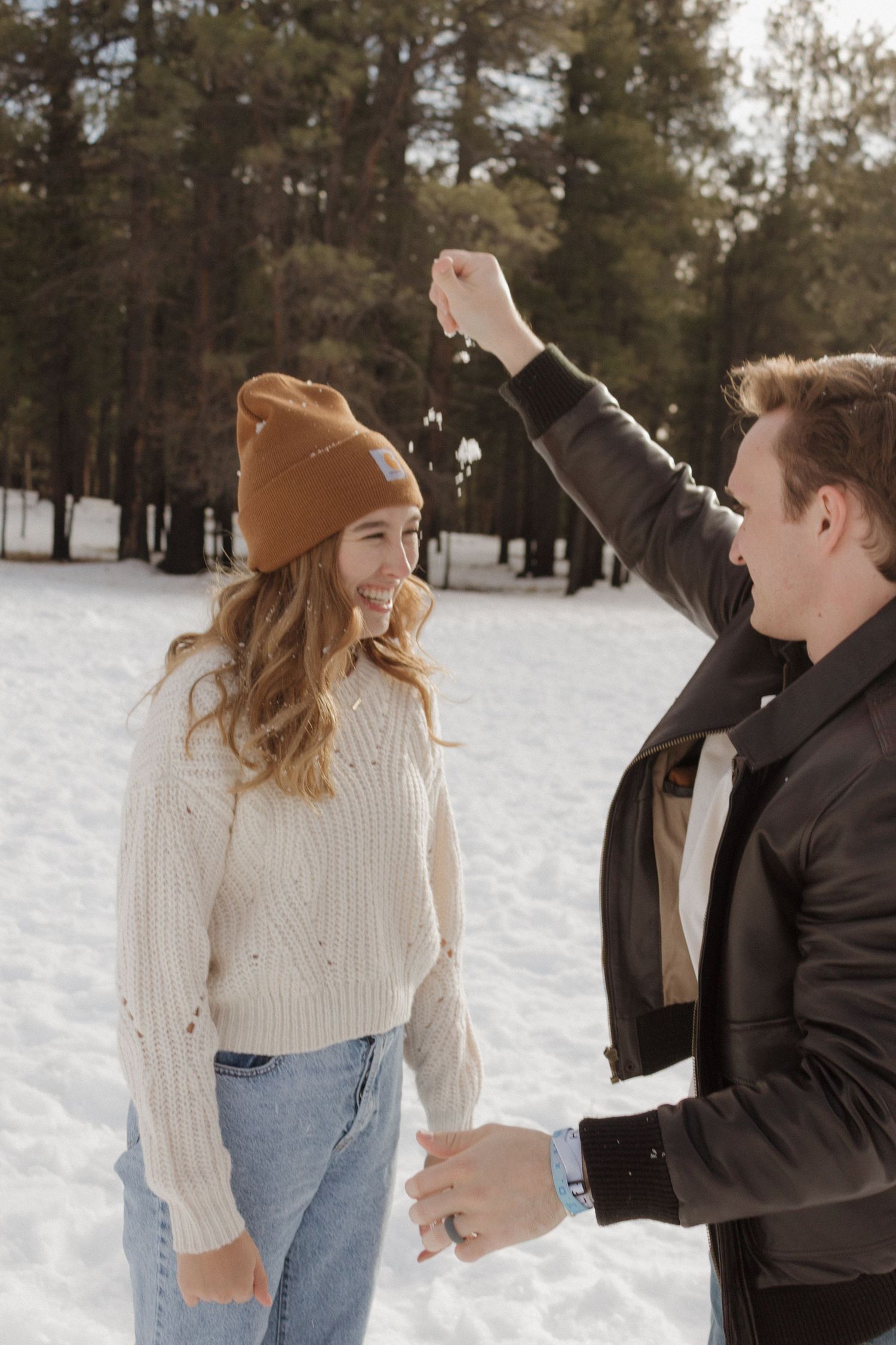 A couple shares a playful moment in the snow.