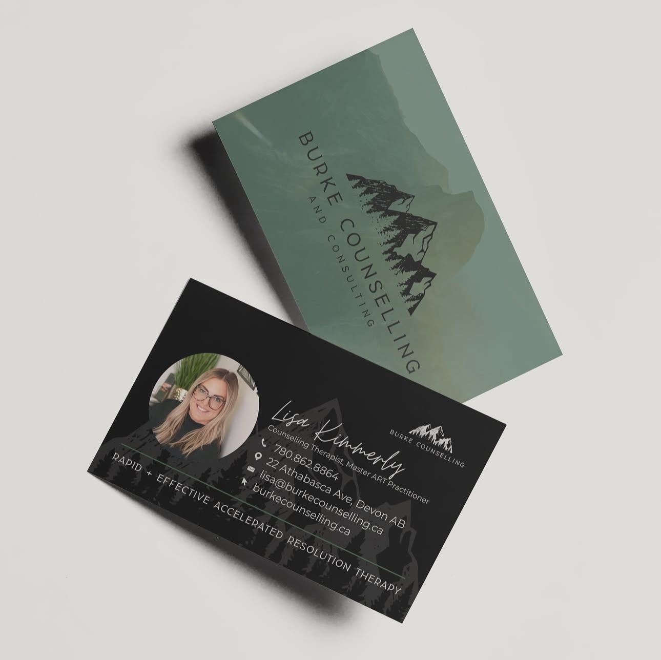 Business cards displaying a minimalist mountain logo design in sage green and black colors on a light background.