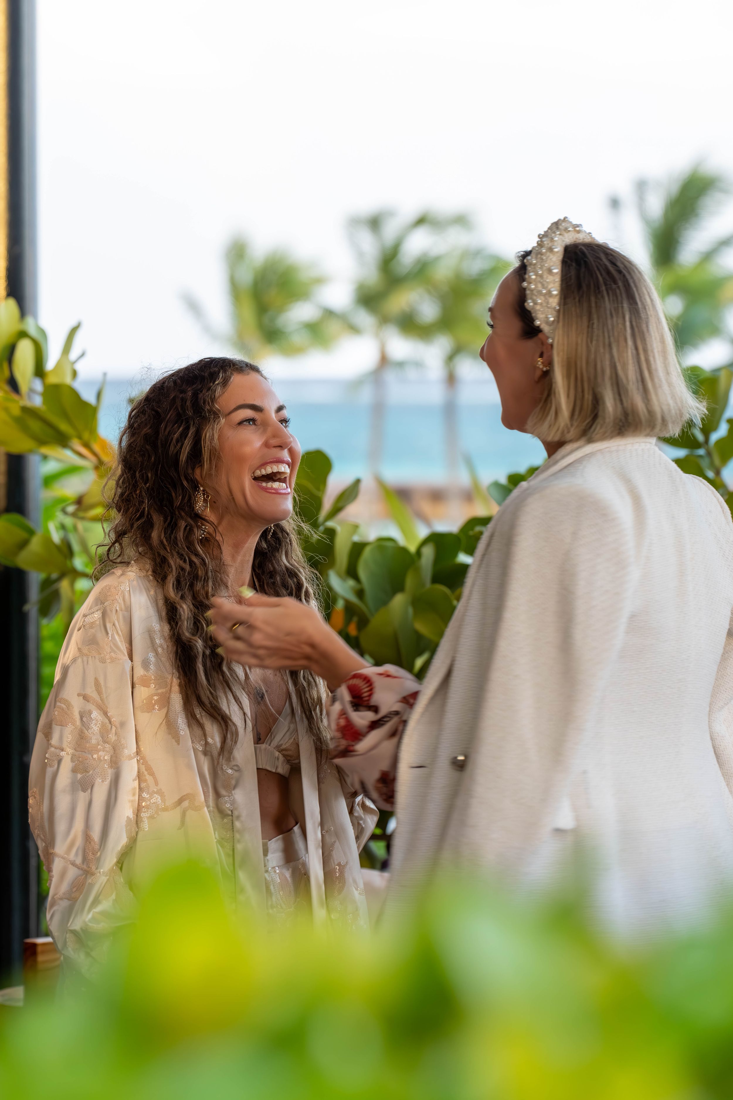 Two people sharing a laughing moment on a tropical balcony with ocean views.