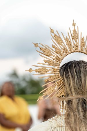 Close-up of an ornate gold sunburst crown headpiece against a soft-focus background.
