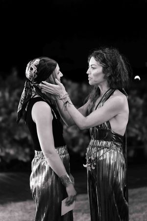 Black and white artistic portrait of two performers in metallic costumes sharing an emotional moment.