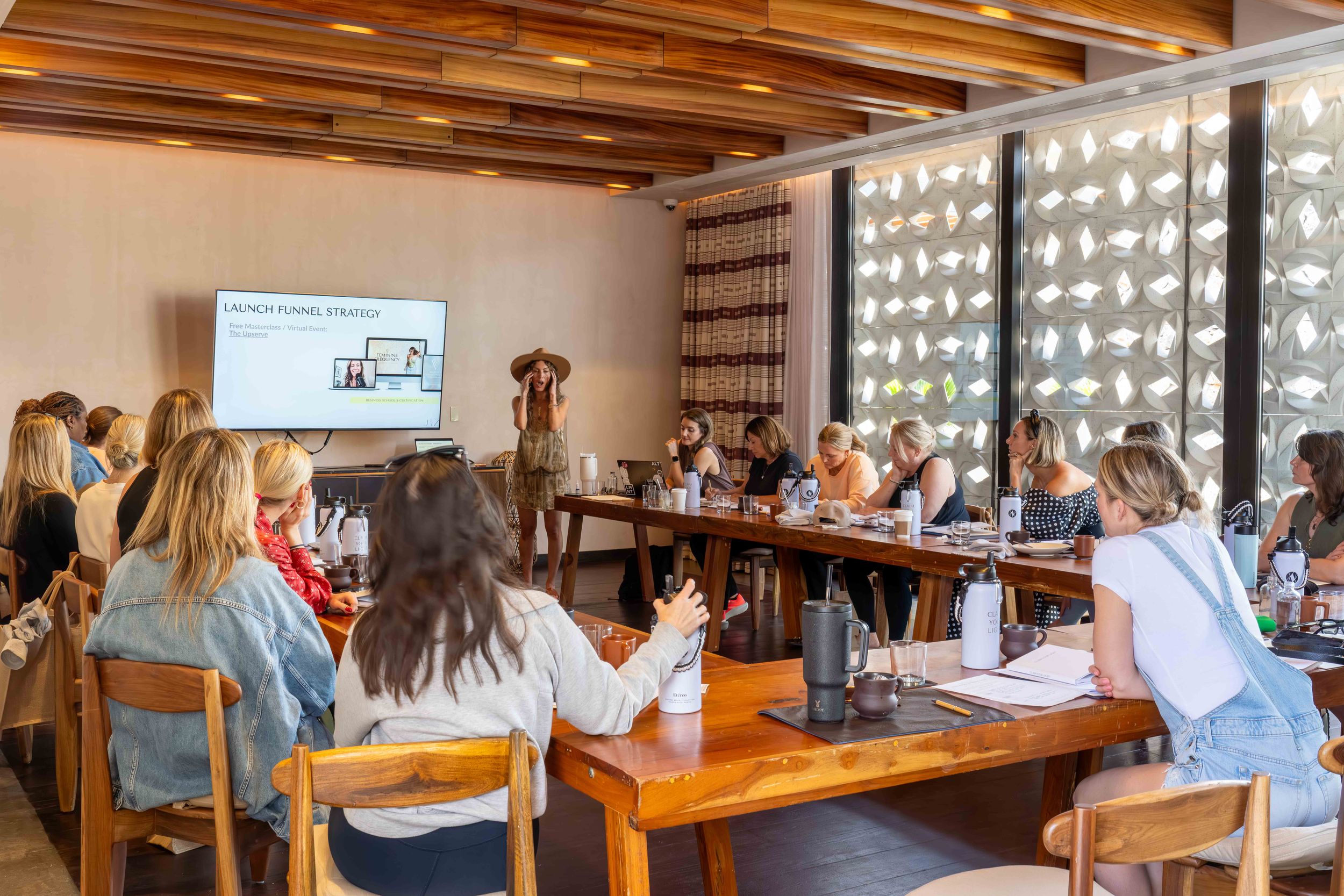 Business meeting or workshop in modern conference room with wooden tables and decorative ceiling.