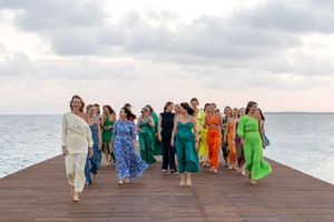 Group photo of people wearing colorful dresses walking together on oceanfront boardwalk.