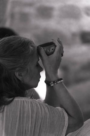 Woman in white takes a photo in dramatic black and white lighting.