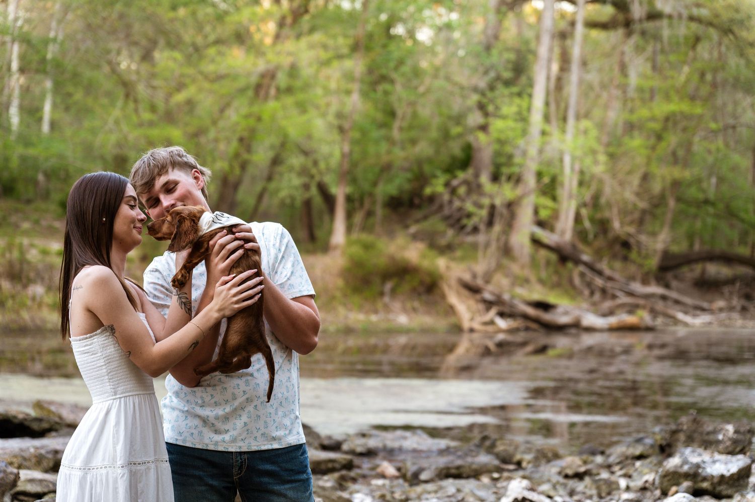 A romantic couple shares an intimate moment at sunset with golden sunlight streaming through Spanish moss.