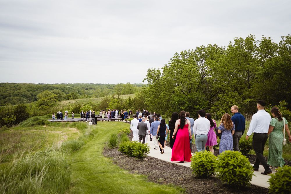 People gathered for an outdoor event on a hillside path surrounded by lush greenery and natural landscape.