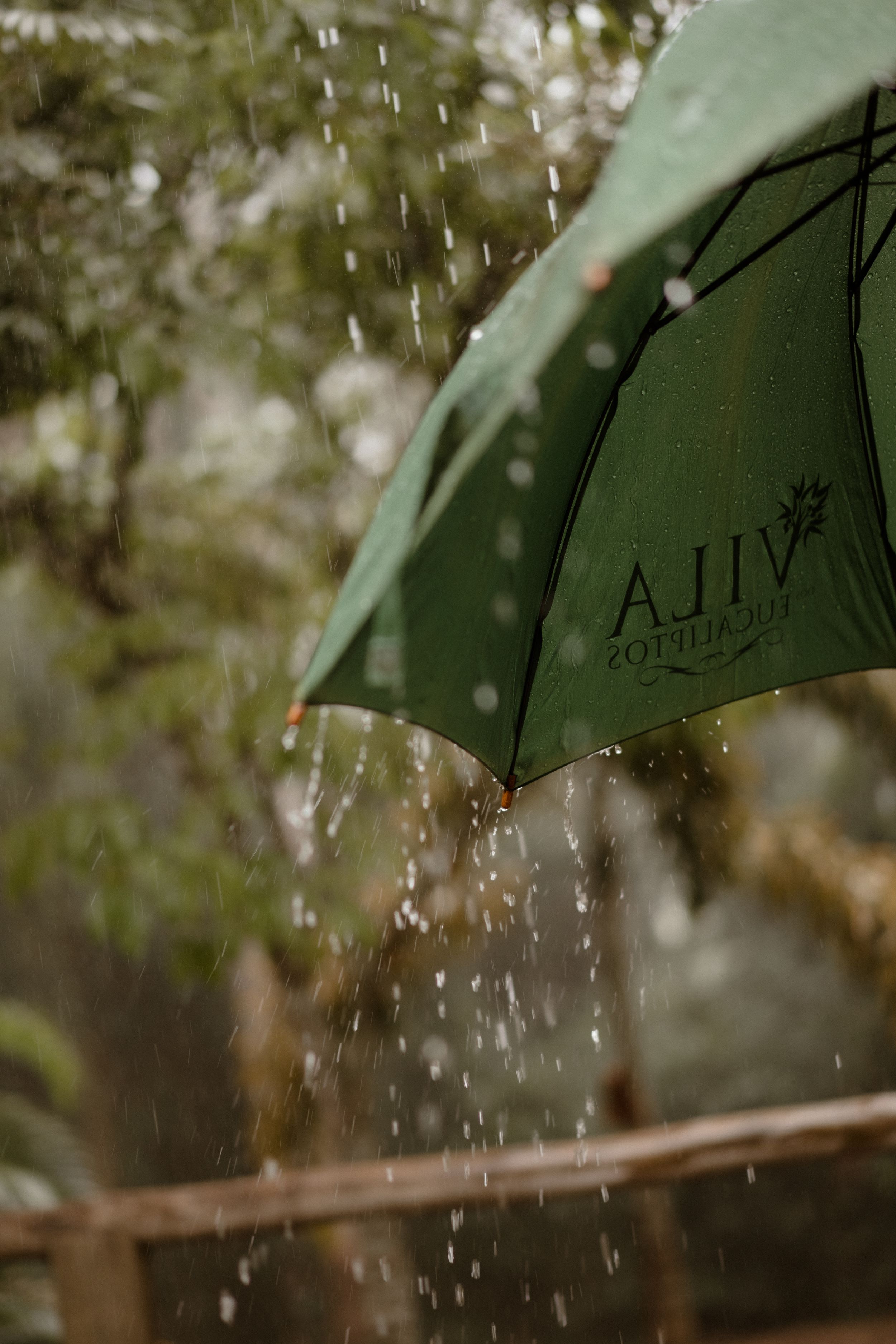 Water droplets falling on a green umbrella during a rainy outdoor event.