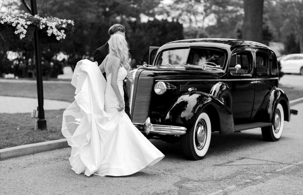 Elegant black and white photo of a classic 1930s Buick automobile with white dress against vintage style car.