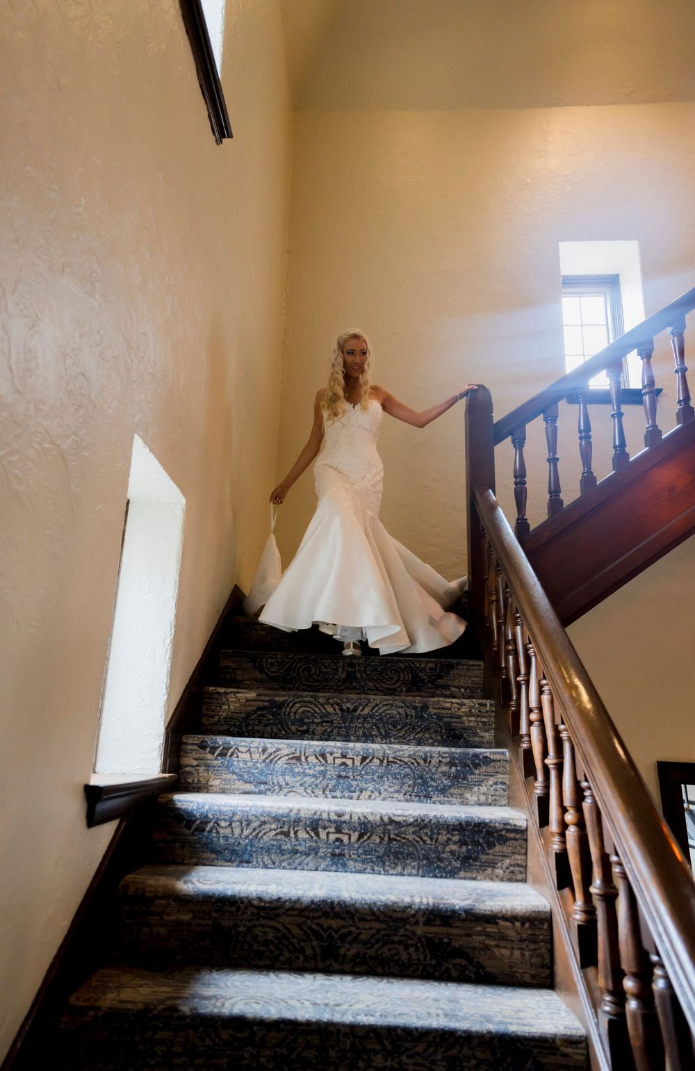 A bride in a flowing white dress descending an elegant staircase.