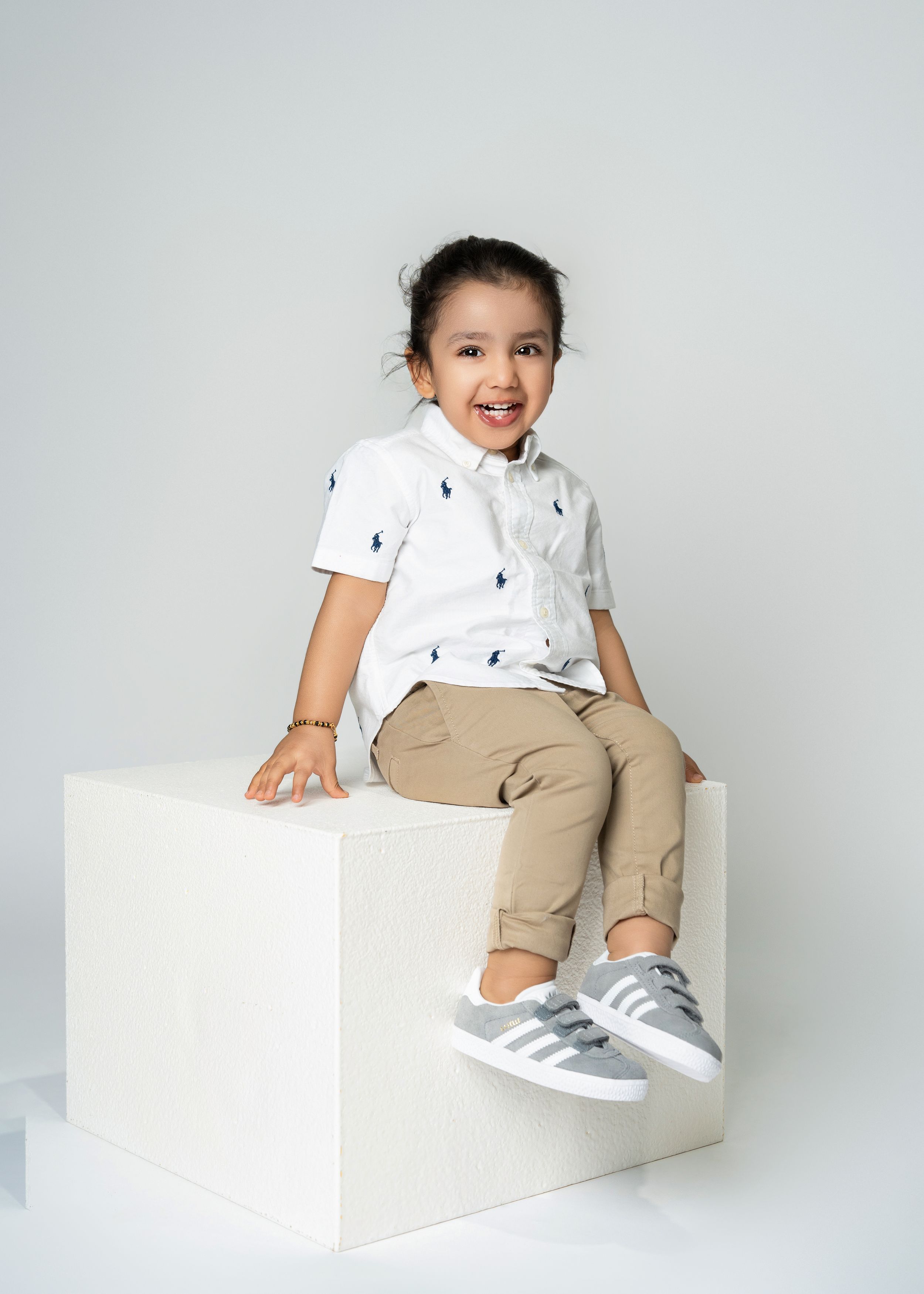 a young boy smiles while sitting on a white cube