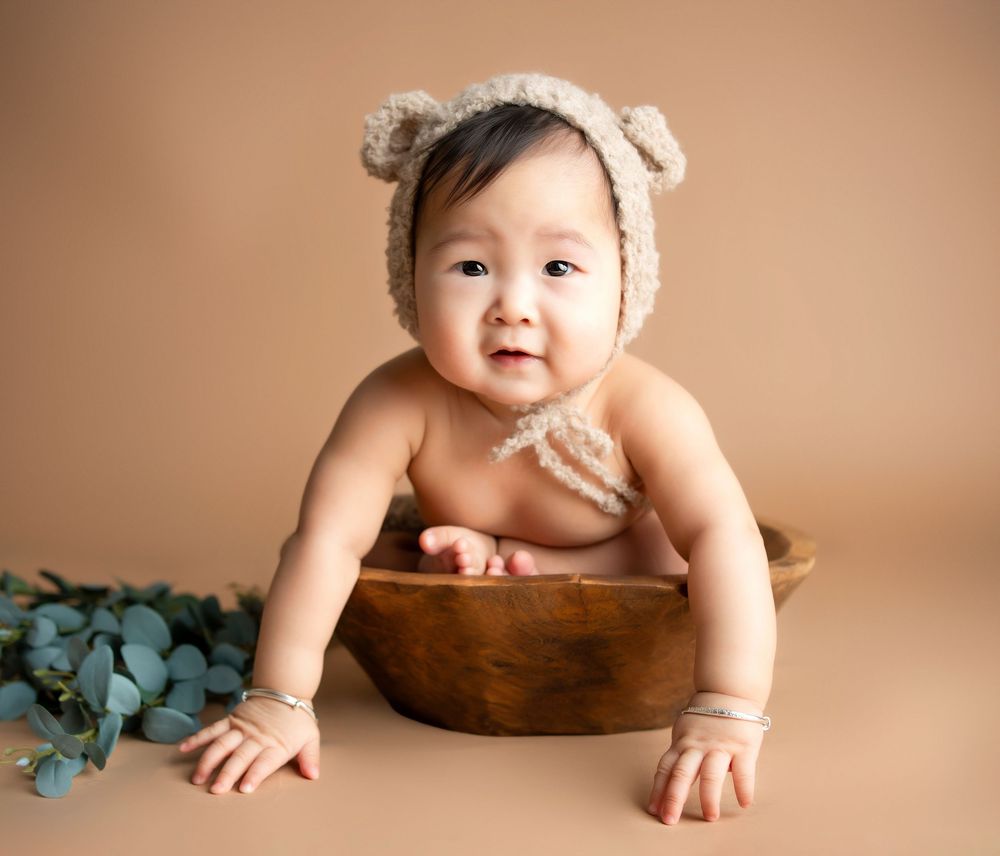 a baby sits in a basket wearing a hat with bear ears during photos with a minneapolis photographer