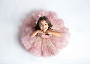 a young girl looks up while wearing a pink princess dress