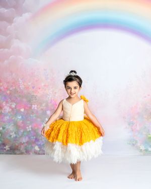 a young girl in a yellow princess dress rests her hands on the sides of her skirt